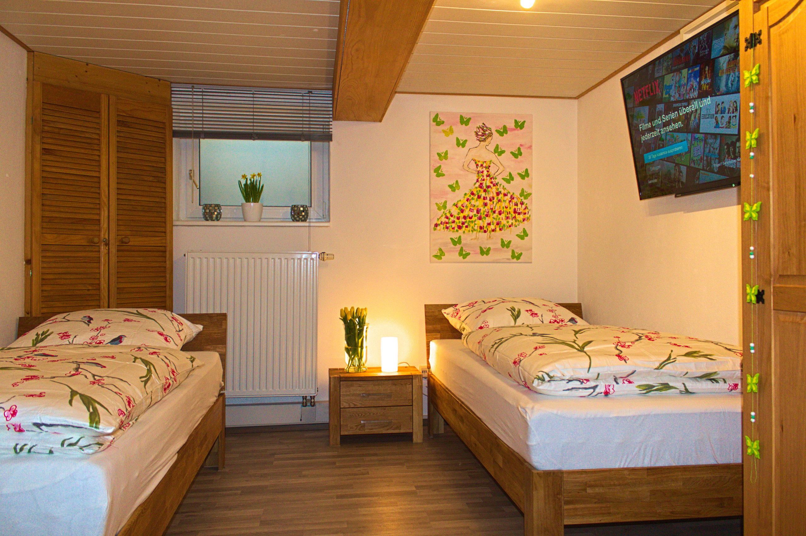 Schlafzimmer mit 2 zusammenstellbaren Betten und großem Smart-TV